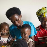 Three women feeding their young toddlers while they are sitting on their laps 